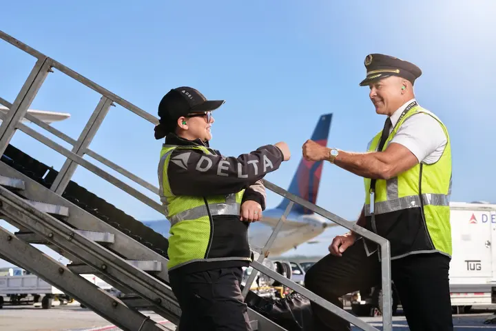 Delta pilot and ground agent giving fist bump on the ramp