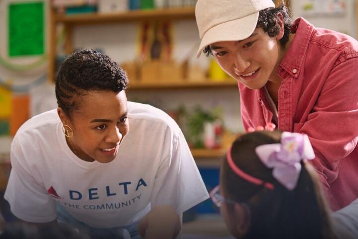 Delta employee volunteer smiling while interacting with a young girl.