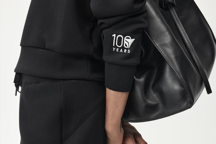 Profile shot of woman wearing black spanx outfit embroidered with Delta Centennial logo.