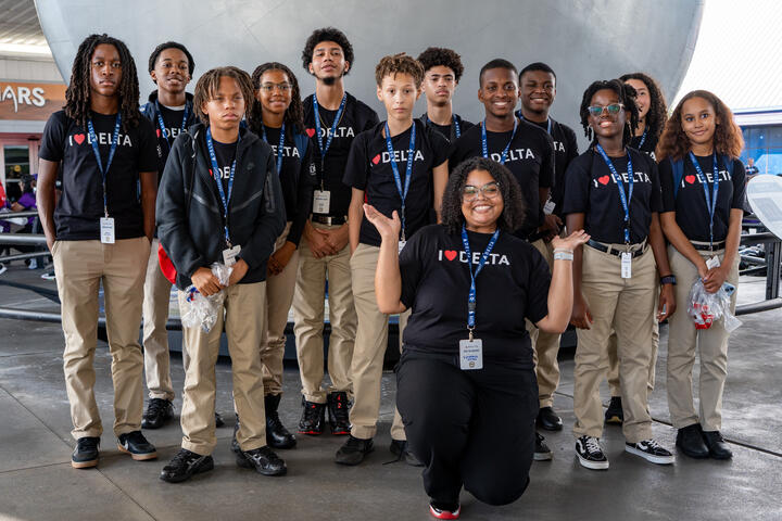 DREAM flight participants posing for in front of a large metallic structure wearing matching black Delta t-shirts.