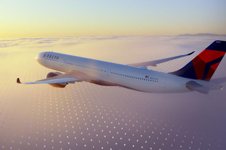 A Delta jet flies above a cloud layer at sunset, with a faint digital grid pattern overlaid across the sky.