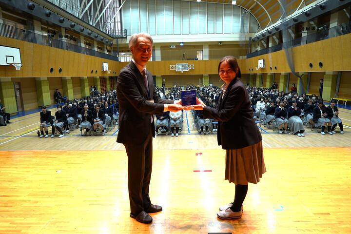 Aki Yokosawa presents a plaque to a student to appreciate miles donations
