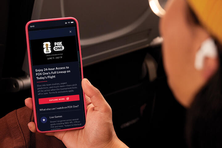 Passenger viewing FOX One content on a smartphone during a flight.