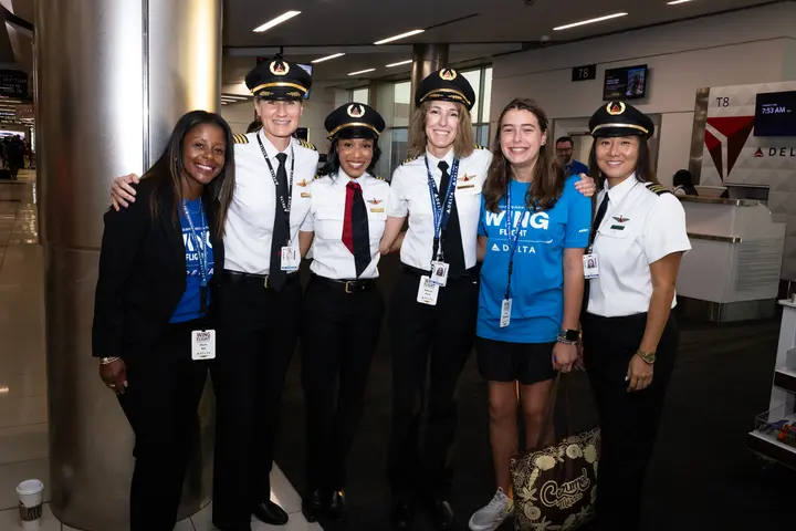 WING Flight participant poses with Delta pilots and aviation professionals at the airport.
