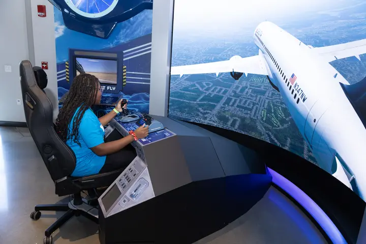 Student uses a flight simulator exhibit at Flight Works Alabama during a WING Flight visit.