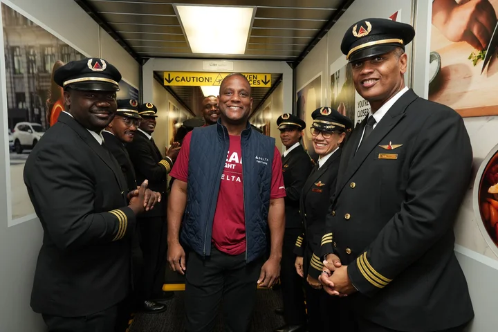 Delta pilots and flight training team members gather in a jet bridge to welcome students participating in the DREAM Flight program.