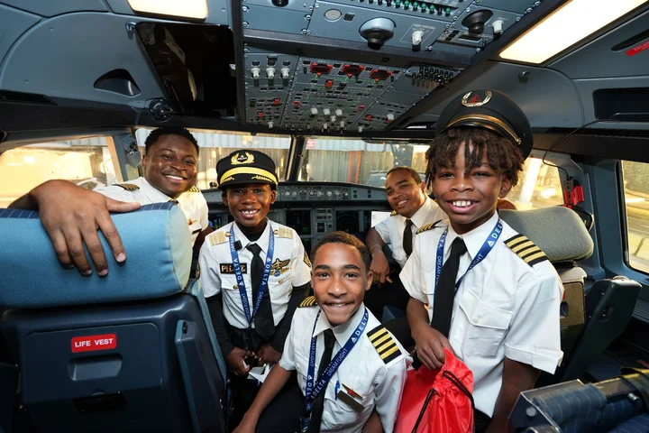 DREAM Flight participants pose with flight crew members in an aircraft cockpit during a behind-the-scenes aviation experience.