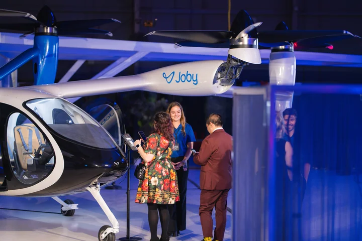 Guests view a Joby electric air taxi aircraft display during a Delta event.