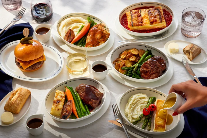 Selection of chef-curated entrée options, bread, wine and beverages served on a table, showcasing the Delta One dining experience.