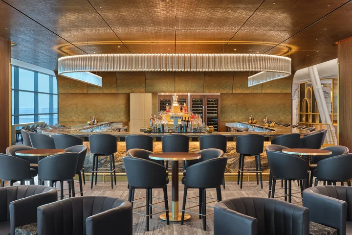 Upscale airport lounge bar with modern seating, marble accents, and a large illuminated chandelier overhead.