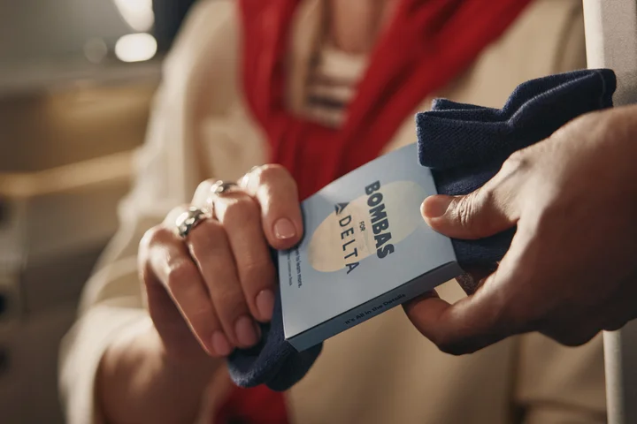 Customer receives a pair of Bombas socks while seated in a Delta One suite.