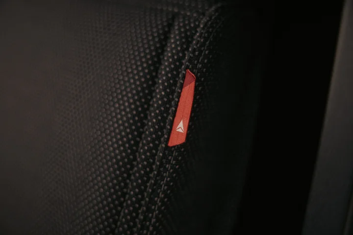 Close-up of a textured black seat surface featuring a small red Delta-branded fabric tag.