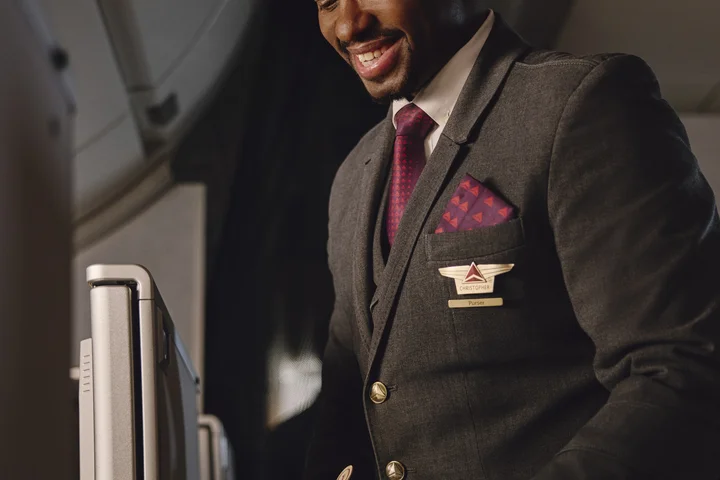 Flight attendant presents a welcome drink and snack service in the Delta One cabin.
