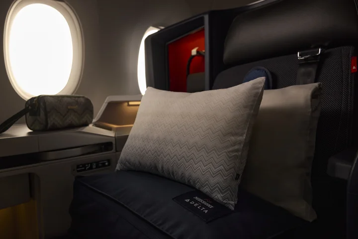 Delta One suite featuring premium bedding, pillows and an amenity kit by the window.