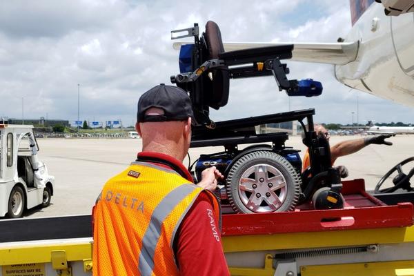 A Delta ramp agent loads a wheelchair onto a plane.