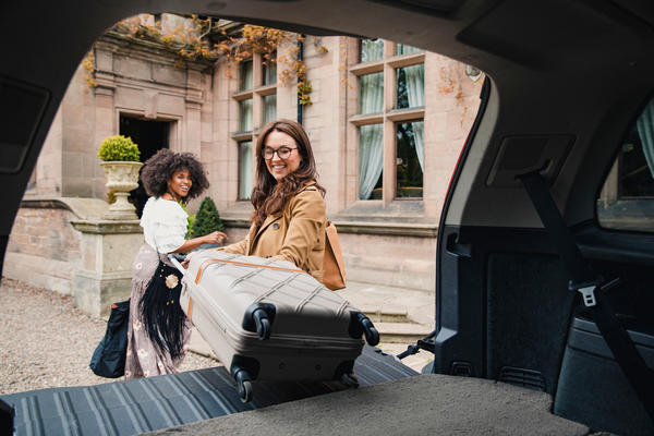 Two people unload suitcases from their vehicle in this stock photo taken in April 2019.