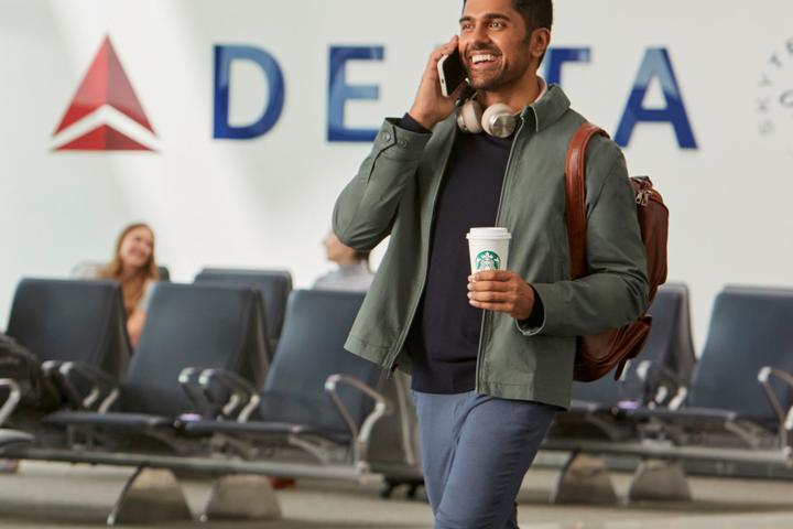 Delta customer en route through airport enjoying Starbucks beverage