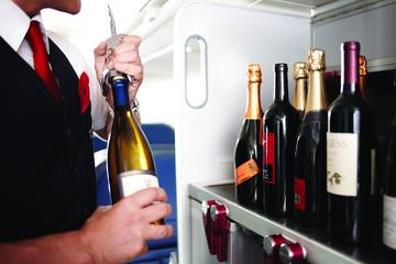 Flight attendant selecting and preparing wine from a service area