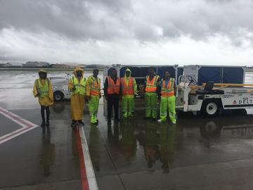 Employees on ramp donning rain gear