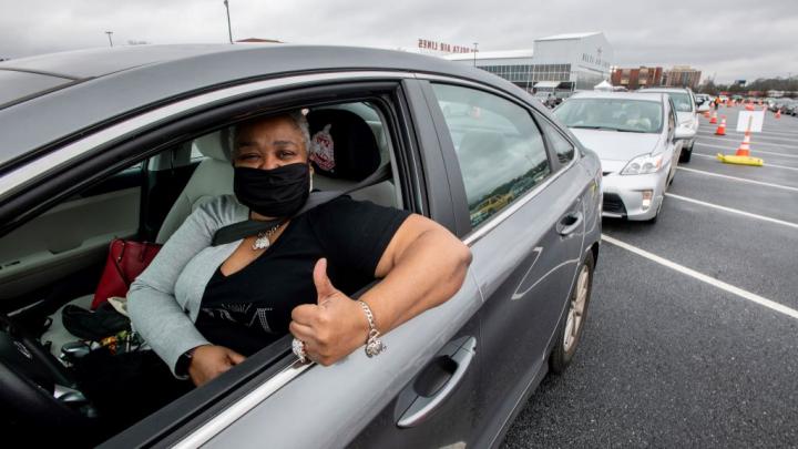 A woman gives a thumb's up at a Delta vaccination site.