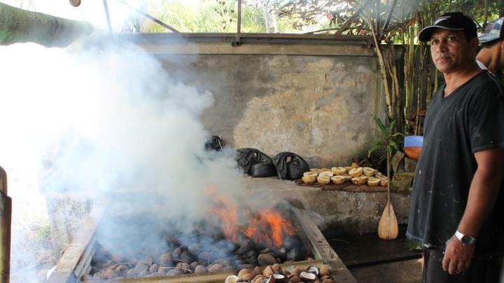 A Tahitian grilling food over an open flame