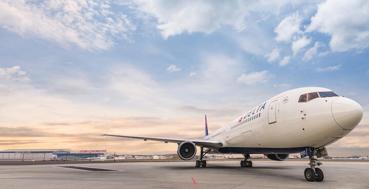 A frontal view of Delta's Boeing 767-400 model sits on the runway while a wisped sky overlooks. 