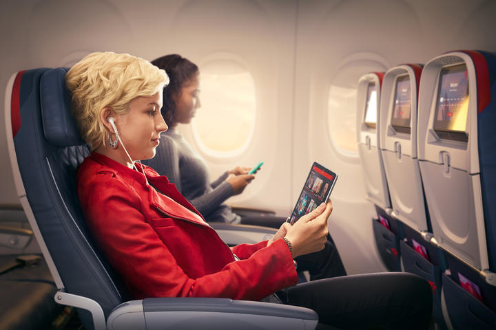 Customers use mobile devices while seated in Delta Comfort+.