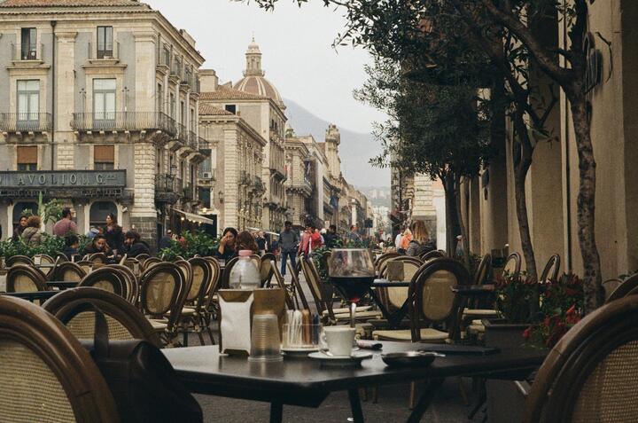 A scenic street in Catania, Sicily with cafe tables and chairs