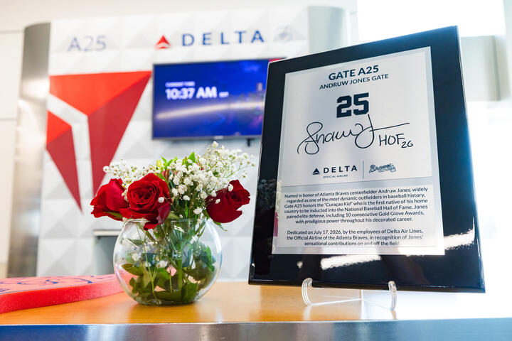 Commemorative plaque honoring Andruw Jones at Delta Gate A25 displayed beside a vase of red roses, with Delta branding visible in the background.