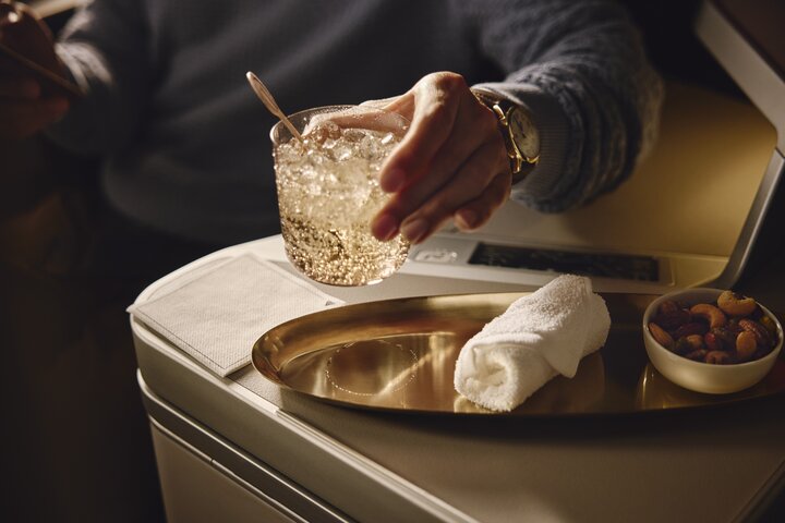 Beverage and mixed nuts served on a tray table in a Delta One suite.