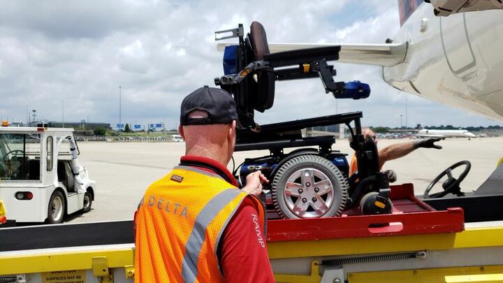 A Delta ramp agent loads a wheelchair onto a plane.