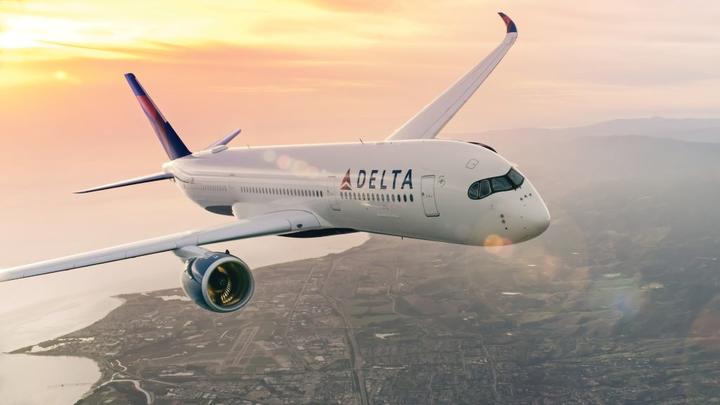 Delta A350 flying above a city at sunset.