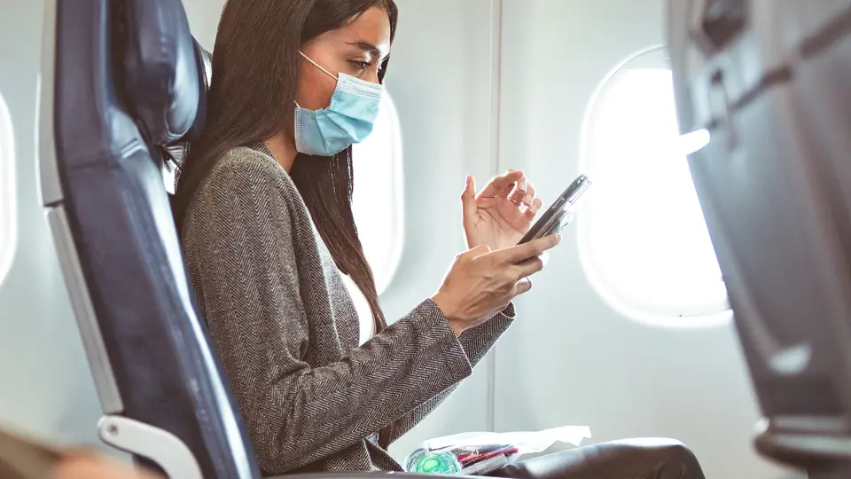 Delta customer in mask at seat with phone