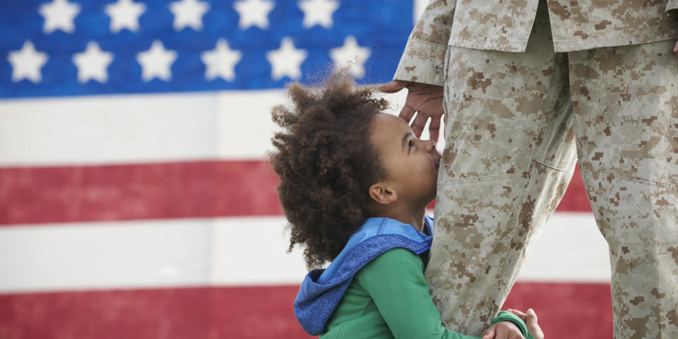 A child hugs a service member in uniform.