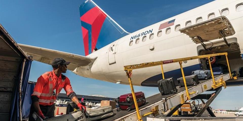 A Delta employee loads baggage onto a plane.