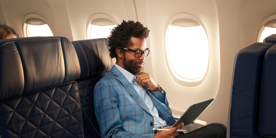 A man works on a tablet while seated in Delta domestic first class.