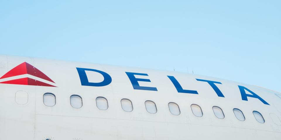 The side of a Delta aircraft against a blue sky