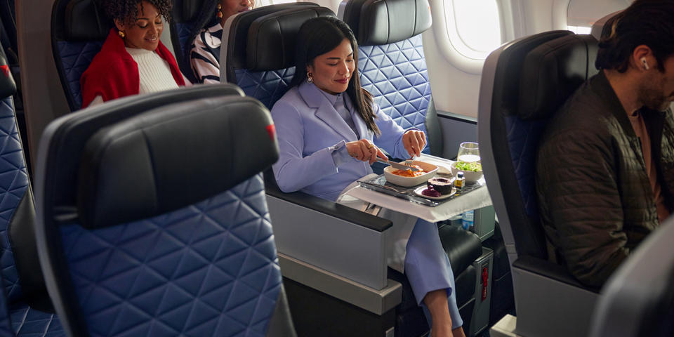 A Delta customer seated in Delta Premium Select enjoys a meal.