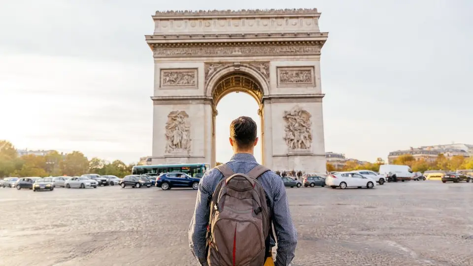 A traveler stands in front of the Arc de Triomphe in Paris, France.