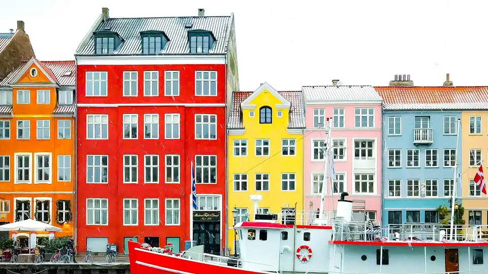 Nyhavn district with boats on water canal and colorful row of old houses in Copenhagen, Denmark