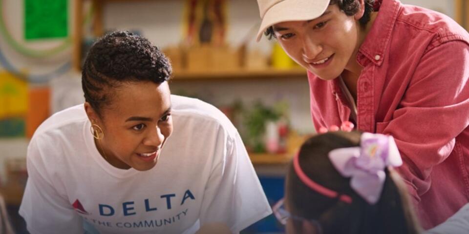 Delta employee volunteer smiling while interacting with a young girl.