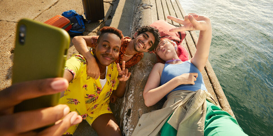 Three people take a selfie next to a body of water