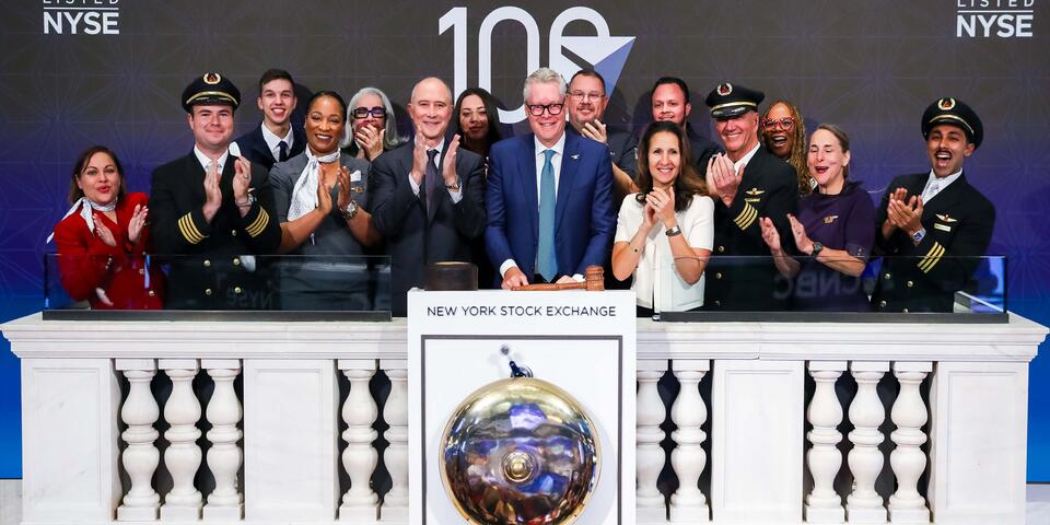 Ed standing in front of the NYSE bell with a group of employees, all clapping