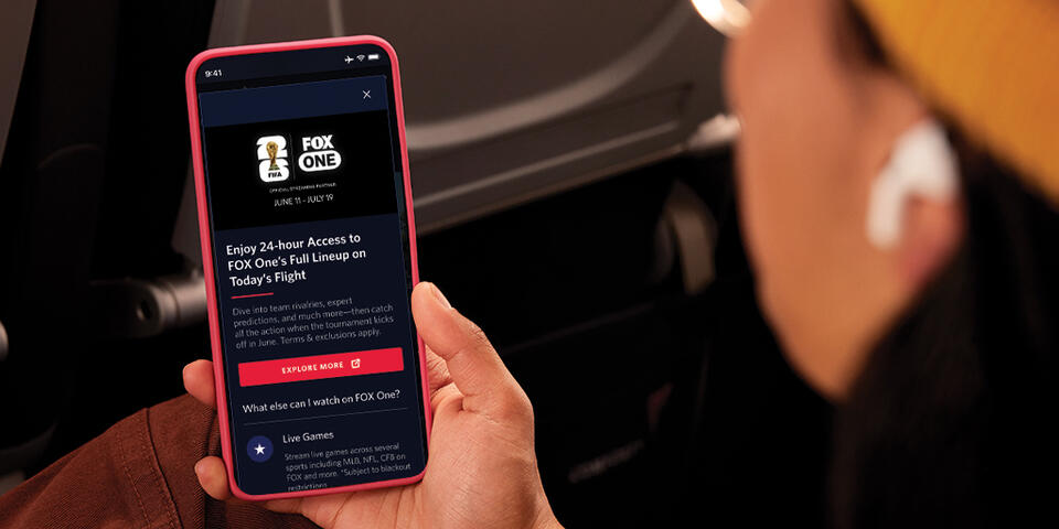 Passenger viewing FOX One content on a smartphone during a flight.