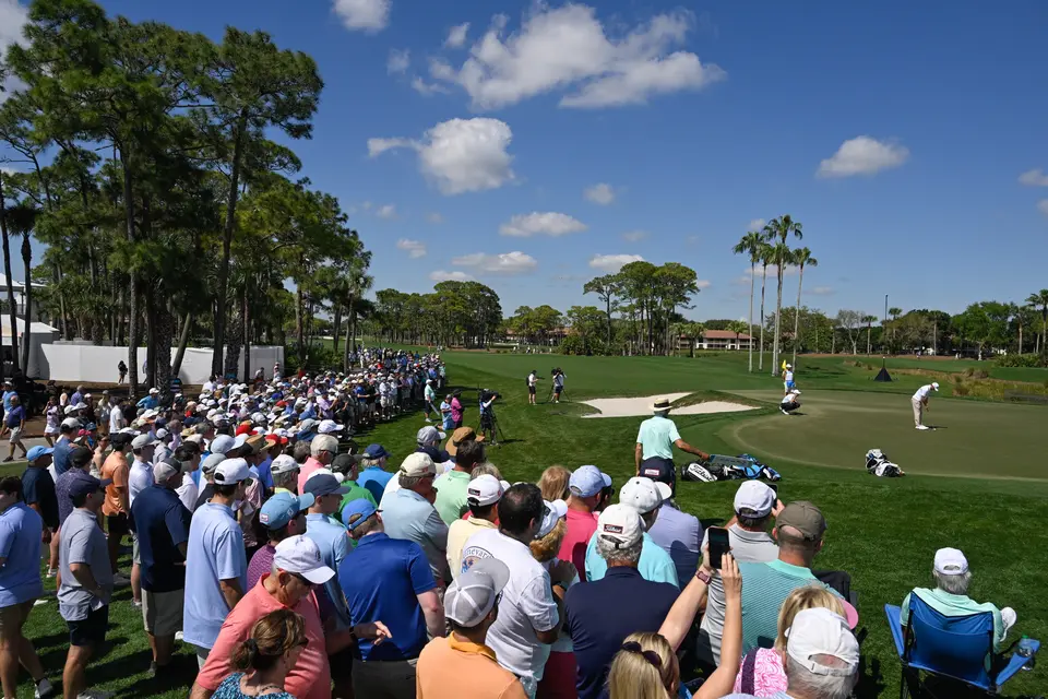 Fans surround a golf green while attending a PGA Tour event.