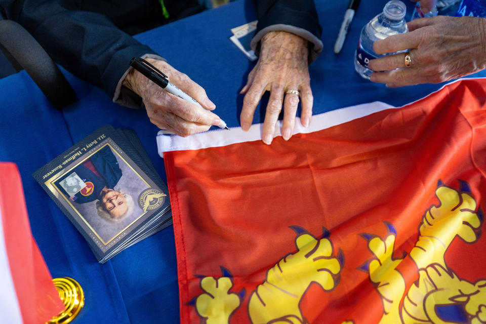 2Lt. Betty Rosevear signs memorabilia during a lunch that preceded the sendoff of more than 40 WWII veterans to Normandy, France, for the 79th annual commemoration of the 1944 D-Day invasion. 