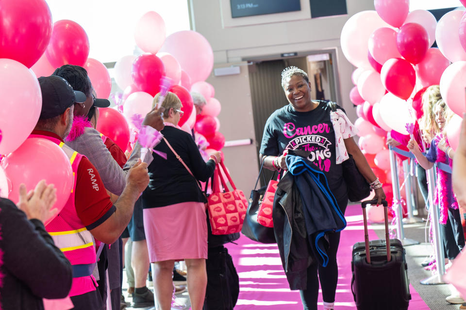A breast cancer survivor walks down a pink runway after disembarking the Breast Cancer One charter flight.