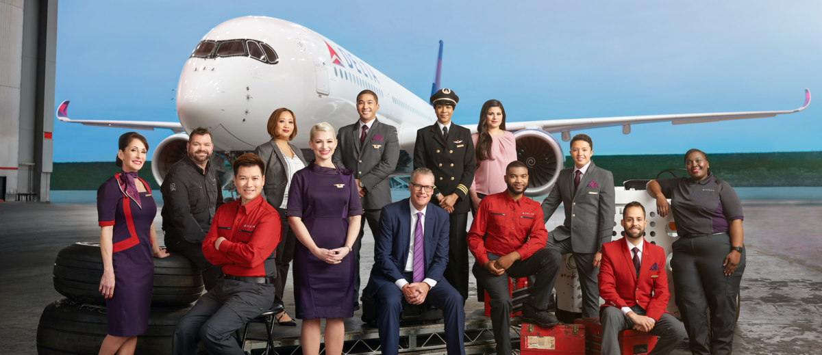 Ed, surrounded by Delta crew, in front of a large plane.