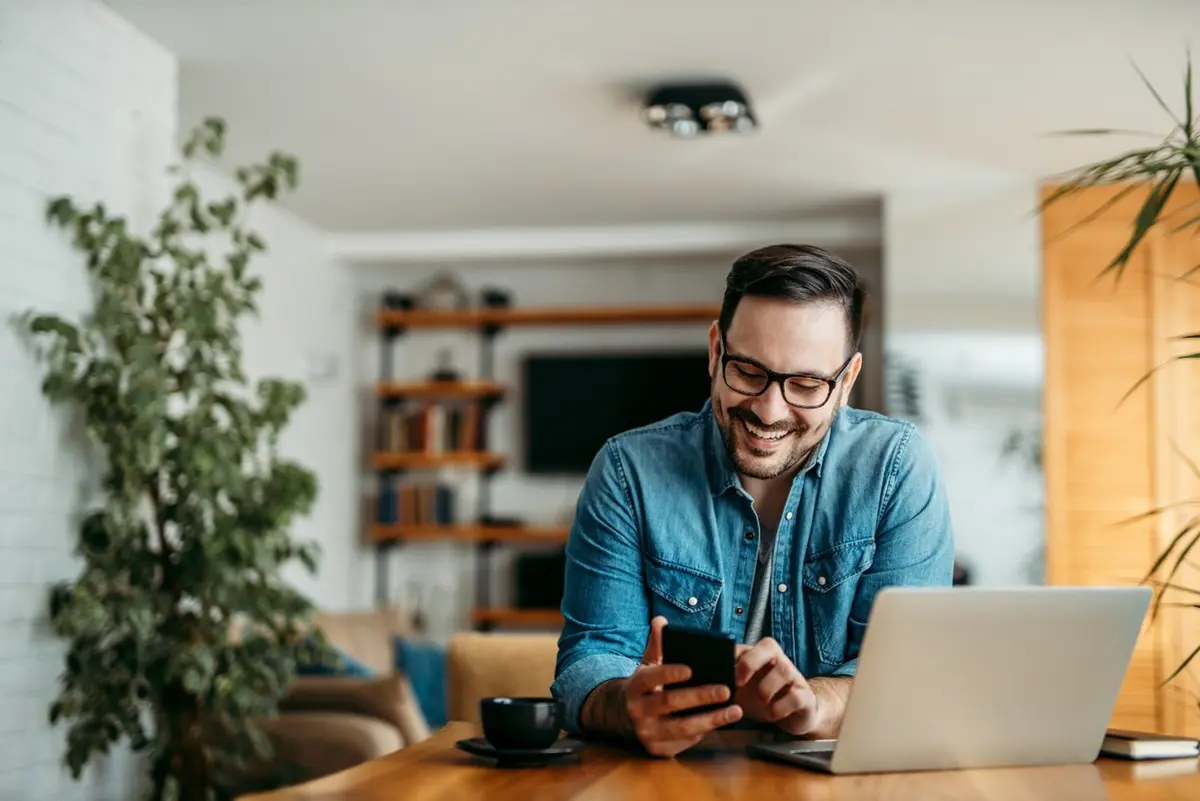 A man uses a mobile device and computer.