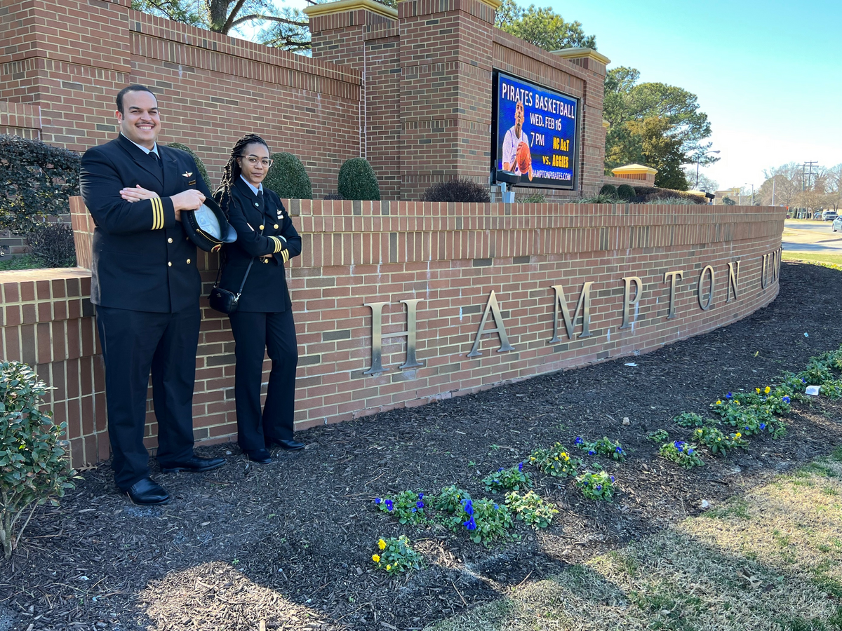 Two aviators stand outside of Hampton University.